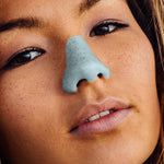 Load image into Gallery viewer, Close up view of woman with freckles wearing Nöz blue tinted sunscreen on her nose
